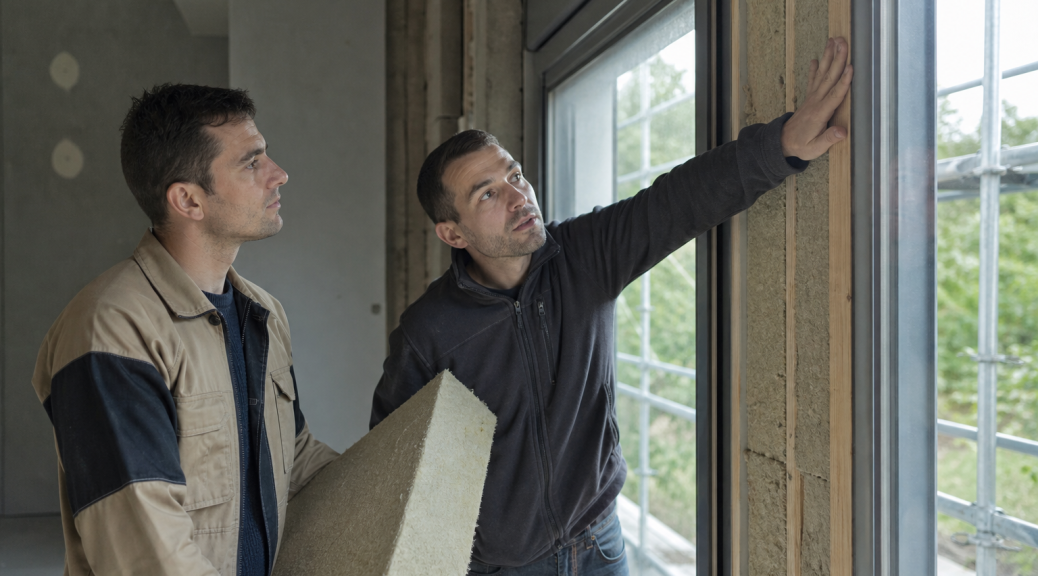 Artisans posant un panneau isolant près d'une fenêtre